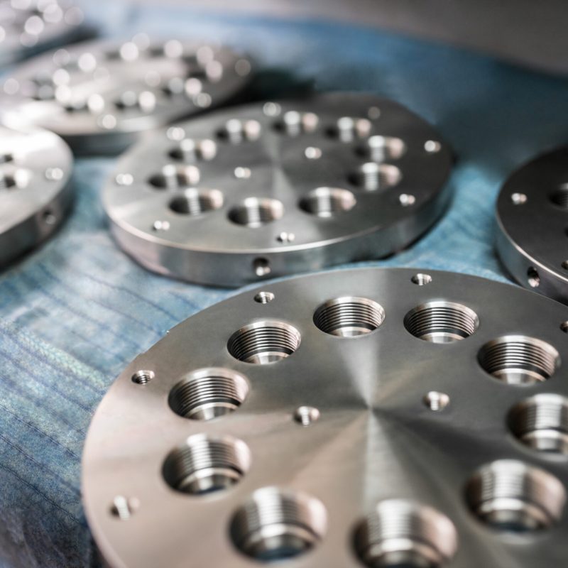 Close-up chrome metal circles with holes lie on shelves awaiting transportation and marketing. Concept manufacturing of metal components for mechanical engineering