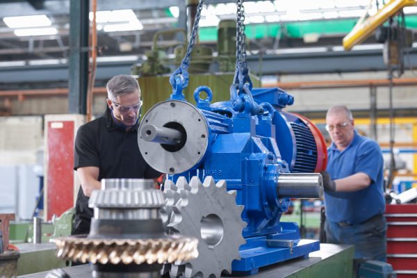 Engineers assembling industrial gearbox in engineering factory